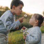 May contain two people blowing dandelion seeds.
